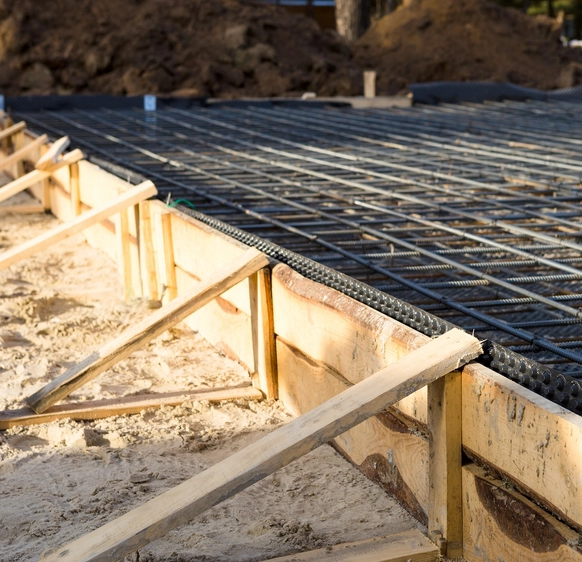 Coffrage en bois avec armature en acier prêt pour le coulage du béton. La structure est soigneusement préparée pour garantir une dalle solide et durable sur un terrain sableux